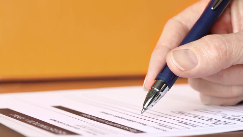 Hand van persoon die met een pen een formulier invult.