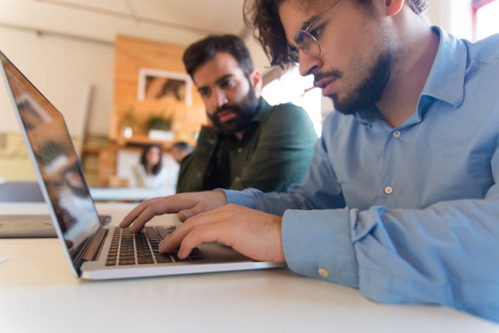 Twee mannen kijken met verbaasde uitdrukking naar een laptop.