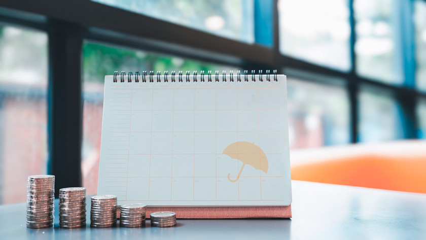 Kalender met stapels muntstukken, symbool voor de betaling van een levensverzekering.