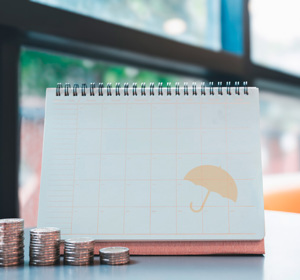 Kalender met stapels muntstukken, symbool voor de betaling van een levensverzekering.