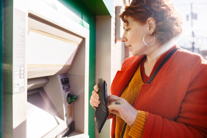 Een vrouw bedient een geldautomaat voor haar banktransactie.