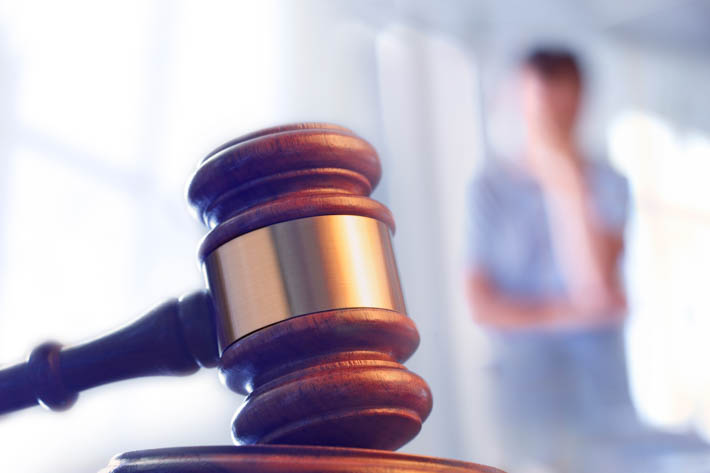 Gavel op voorgrond. Op achtergrond is een persoon wazig zichtbaar.