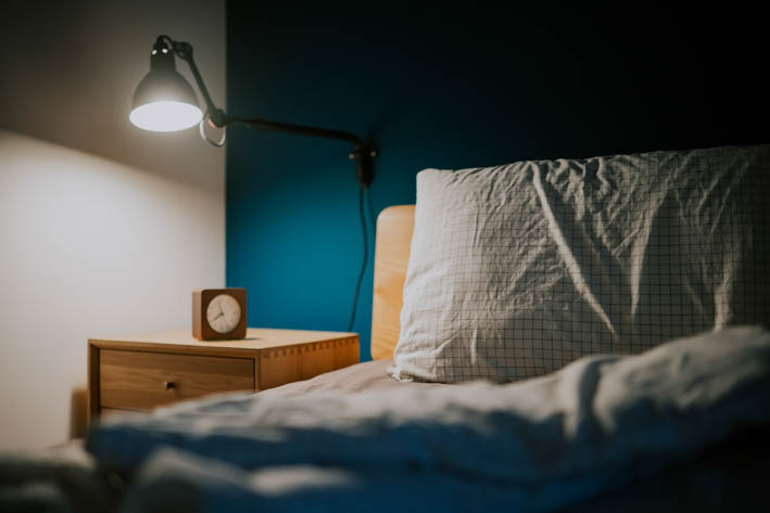Bed met kussen, nachtkastje en een nachtlamp.