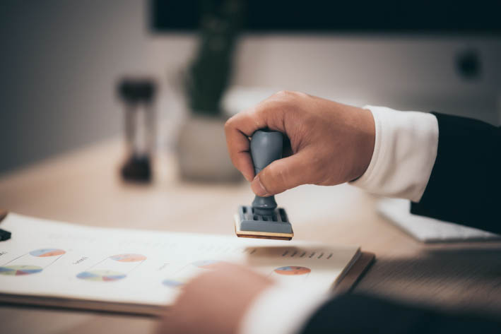 Persoon die stempel op documenten zet.