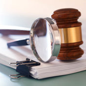 Stapel documenten, met daarop een vergrootglas en een gavel.