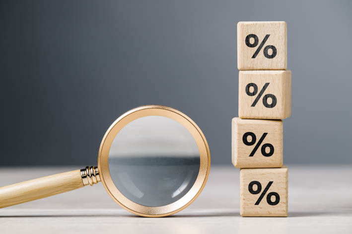 en vergrootglas ligt naast een stapel houten blokken waarop procenttekens staan.