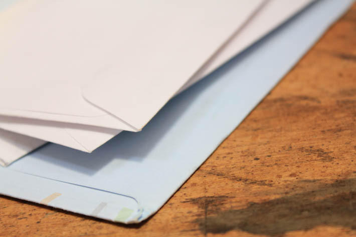 Stapel dichte enveloppen op een houten tafel.