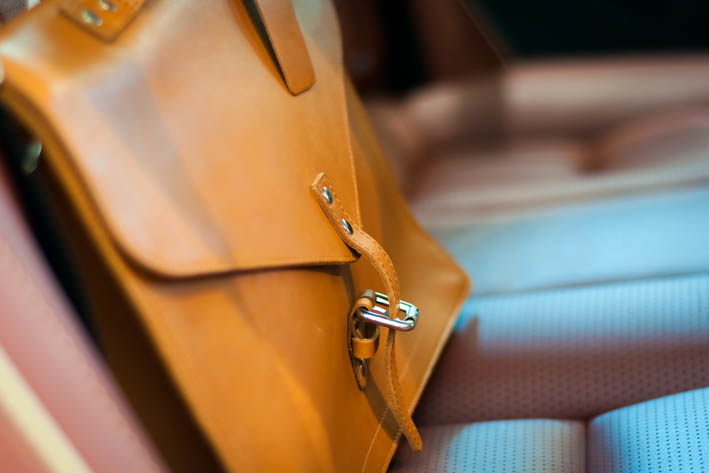 Een bruine leren tas op de achterbank van een auto.