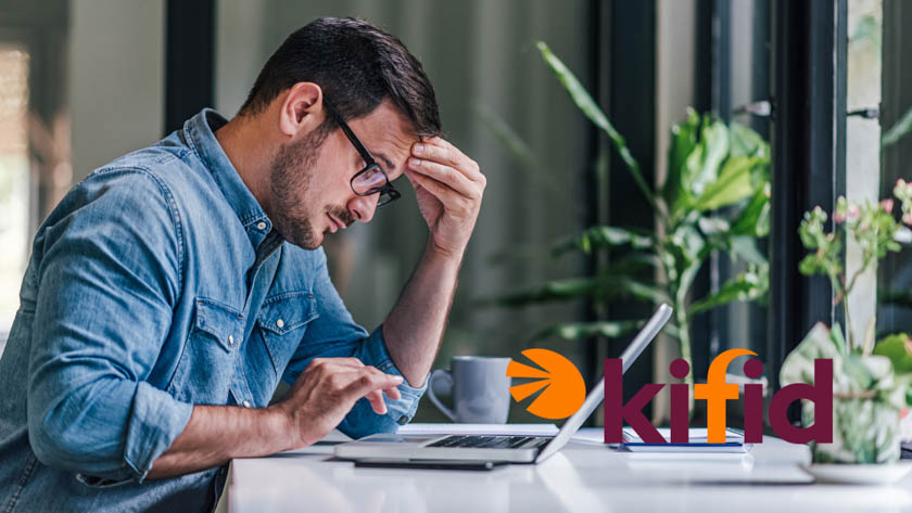 Man zit achter zijn bureau en kijkt naar laptop. Hij houdt zijn hand tegen zijn hoofd en lijkt een zorgelijke uitstraling te hebben.