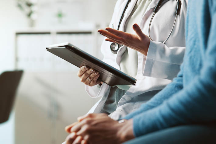 Een dokter en een persoon die met elkaar in gesprek zijn.