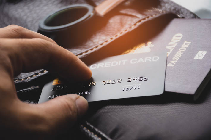 Hand met creditcard en paspoort.