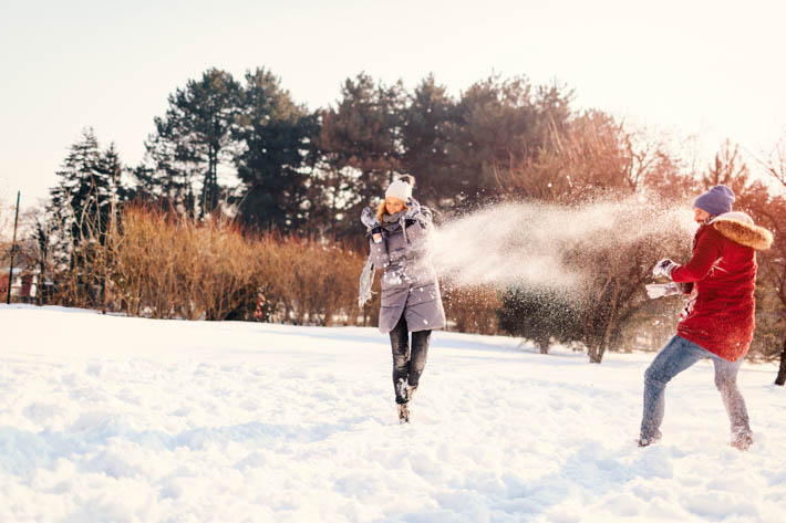 Man en vrouw die samen een speels sneeuwgevecht hebben.