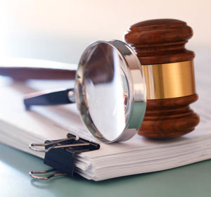 Stapel documenten, met daarop een vergrootglas en een gavel.