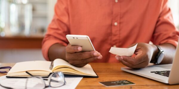 Closeup of man hands using phone to calculate expenses. Man checking invoice balance on mobile phone app. Close up hands of guy taking a closer look at his budget and calculating credit card bills.